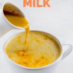 一个水罐把金色的牛奶倒进杯子里的照片