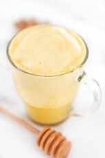 一杯姜黄拿铁和一个蜂蜜勺子的照片